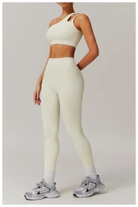 Détail d'une brassière de sport asymétrique crème et d'un legging avec poches