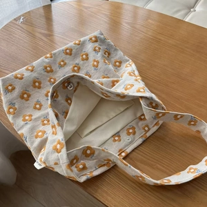 Minimalist canvas tote bag with small yellow flower embroidery and magnetic closure
