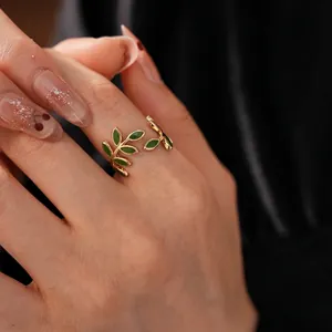 Vintage gold open ring featuring symmetrical green enamel leaves on a model's hand
