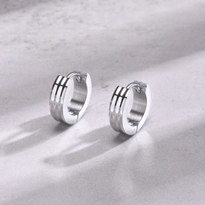 Macro shot of silver stainless steel hoop earrings with three vertical engraved lines