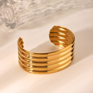 Macro detail of 18K gold stainless steel wide cuff bracelet with layered wavy textures