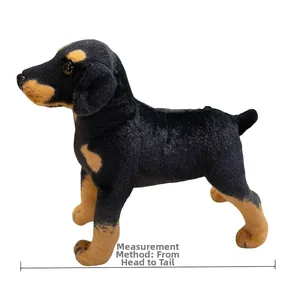 Side view of realistic black and tan stuffed puppy plush toy with measurement scale