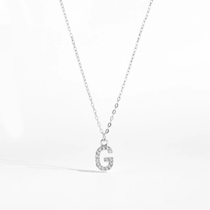 Macro shot of silver letter G pendant featuring micro-set white cubic zirconia stones