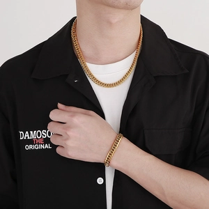 Gros plan d'un mannequin portant un ensemble collier et bracelet gourmette dorés