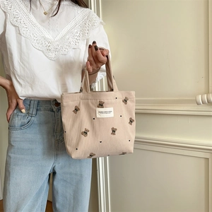 Detail of beige corduroy handbag featuring cute embroidered bears and heart patterns