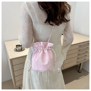 Detail view of pink drawstring bucket bag with natural folds worn by a model