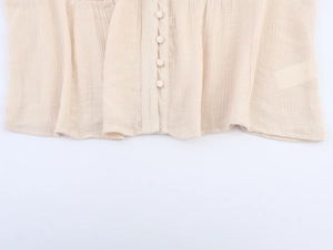 Detail of beige embroidery shirt showing fabric texture and matching covered buttons
