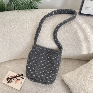 Close-up of grey plush bucket bag with white polka dots on soft fleece surface