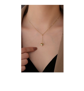 Detailed view of a gold solid heart pendant necklace worn on a vintage style outfit