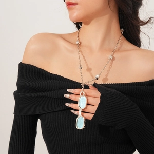 Silver chain necklace with crystal accents and eyeglass-shaped pendant on a model