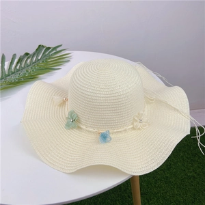 Detail of off-white straw sun hat with mesh flowers and rhinestone accents