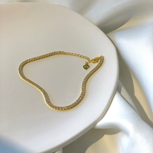Detail of s925 gold-plated tennis bracelet with zircon stones and adjustable heart charm