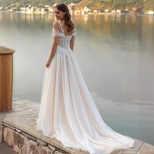 Off-shoulder lace wedding dress with floral embroidery and long tulle train by the lake