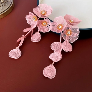 Détail des pétales de fleurs roses en métal avec strass blancs brillants sur boucles