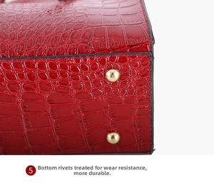 Details einer roten Handtasche mit Krokodilprägung und goldenen Metallschutznieten