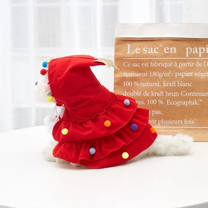 Close-up of red fleece Christmas tree pet cloak with pom-poms on small white dog