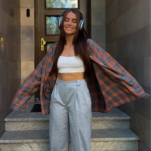 Détail de chemise vintage à carreaux orange et bleu avec débardeur blanc et pantalon large