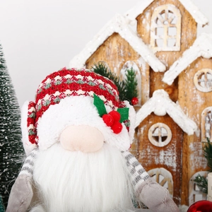 Close-up of a festive Christmas gnome with knitted hat and berry details on a wooden background