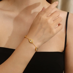 Detail of 18K gold plated bracelet with oval transparent gemstones on a model's wrist