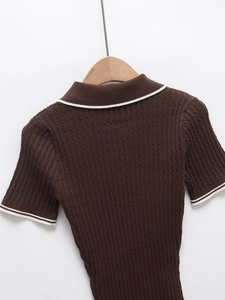 Nahaufnahme des braunen Strickoberteils mit weißen Streifendetails an Kragen und Ärmeln
