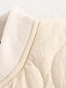 Macro detail of beige quilted jacket featuring a ribbed collar and high-quality stitching