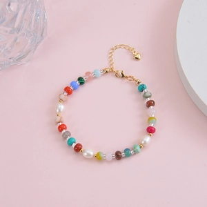 Detail of bohemian colorful beaded necklace with freshwater pearl and gold heart pendant