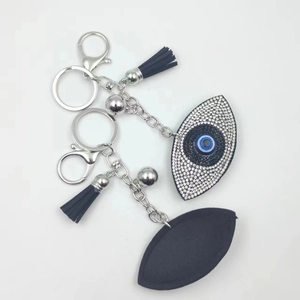 Detail of evil eye keychain with sparkling rhinestones, black leather leaf and silk tassel