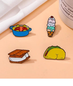 Close-up of enamel pins featuring cartoon food designs like taco and ice cream shapes