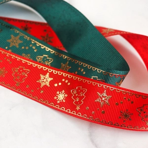 Macro detail of red and green ribbed ribbons with gold Christmas patterns on marble background