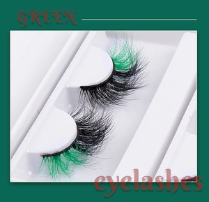 Macro shot of black to green gradient faux mink eyelashes with natural curl on white tray