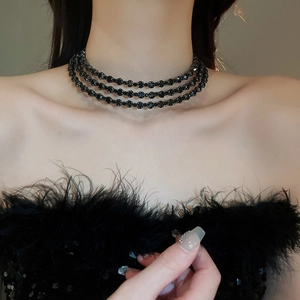 Close-up detail of three-layer black faceted bead choker necklace on model's neck