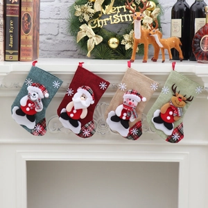 Detail of four linen Christmas stockings with 3D Santa and reindeer hanging on fireplace