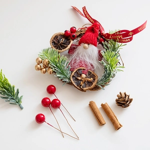Handmade Christmas wreath set with pine cones, red berries and cinnamon sticks on white background