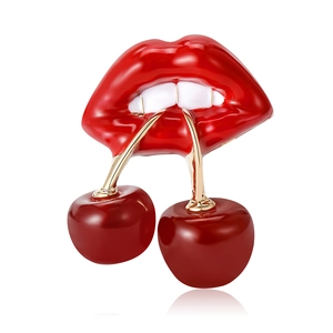 Fashion enamel lips and cherries brooch with gold accents on a polished white background