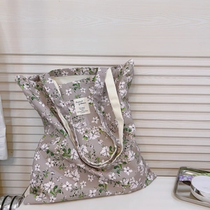 Borsa tote in tela a fiori con manici bianchi su sfondo di legno minimalista