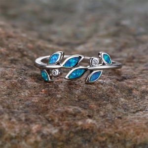 Silver olive leaf ring with blue opal and crystals on a natural stone background