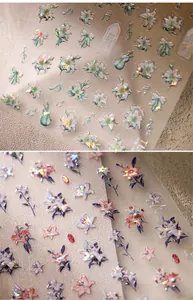 Detail of 3D nail stickers with holographic bows, lilies and pearl accents