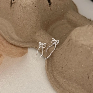 Macro shot of 925 sterling silver bow earrings with polished finish and flowing ribbon detail