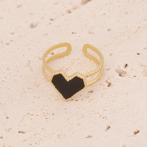Detail of vintage gold heart ring with black oil drip and beaded edges on stone background