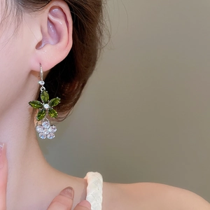 Gros plan de boucles d'oreilles fleurs en zircon vert et blanc portées par un mannequin