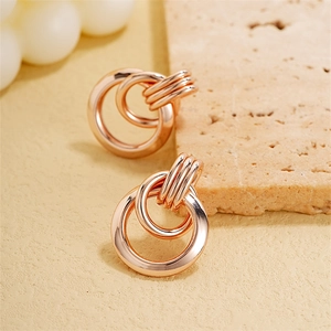 Close-up of interlocking rose gold hoop earrings with polished geometric metal texture