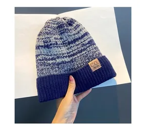 Detail of blue and white knitted hat with textured weave and brown leather brand label