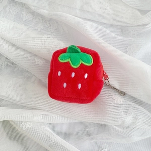 Close-up of a plush strawberry coin purse with green leaves and a silver bead chain