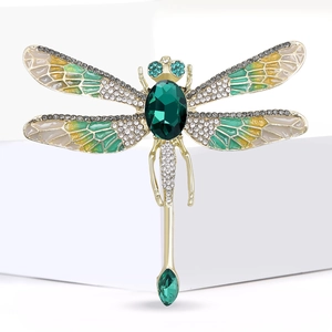 Detail of dragonfly brooch with green oval gemstone, enamel wings and clear crystals
