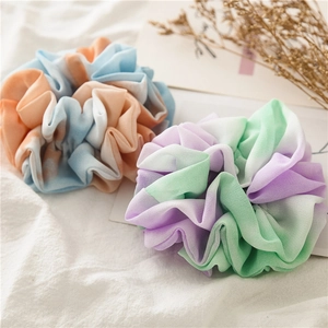 Flat lay of gradient chiffon hair scrunchies in blue-orange and green-purple tones