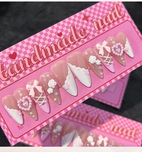 Detailed close-up of handmade press-on nails with 3D pink bows and pearl heart charms
