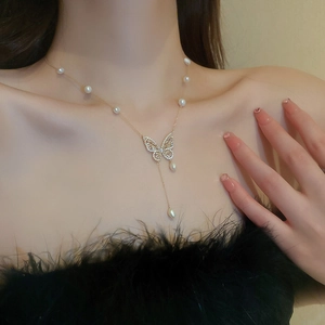 Close-up of gold-plated butterfly necklace with freshwater pearls and tassel on neck