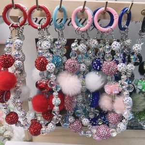 Detailed close-up of colorful beaded phone charms with fuzzy pom-poms and spring rings