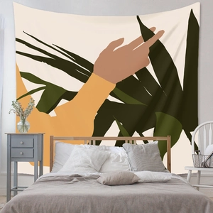 Detail of bohemian wall tapestry with abstract hand and green palm leaf in bedroom