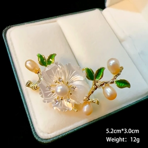 Macro view of a 5.2cm pearl lotus flower brooch with white petals and green leaves